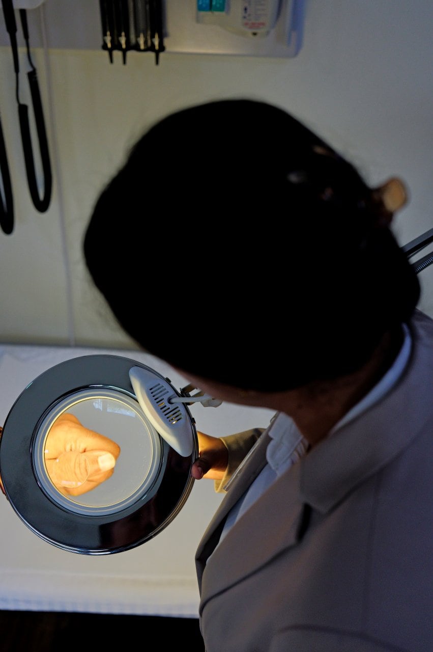 Medical Professional Patient Hand Examination Magnifying Lamp Closeup - integrative healthcare treatment at Healers Clinic Dubai
